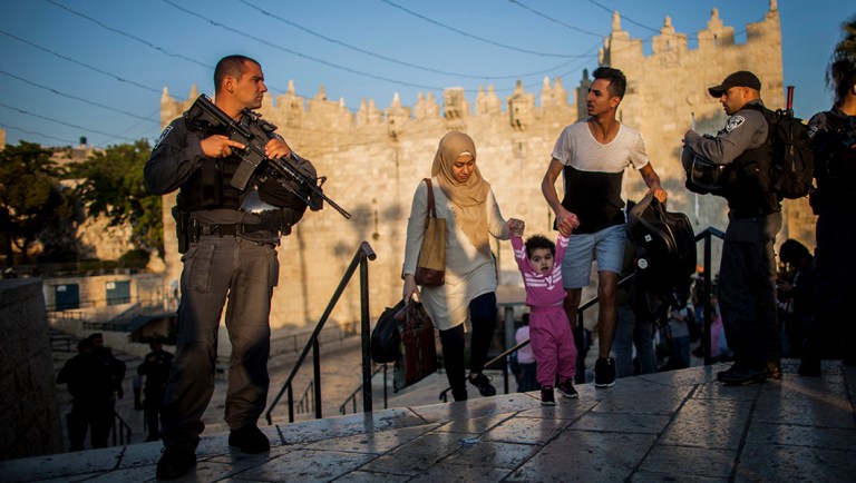 Israeli police officers stand guard as a Palestinian couple lift their child up the stairs outside Damascus gate in Jerusalem, Tuesday, May 15, 2018. Israel faced a growing backlash Tuesday and new charges of using excessive force, a day after Israeli troops firing from across a border fence killed dozens of Palestinians and wounded more than 2,700 at a mass protest in Gaza.
