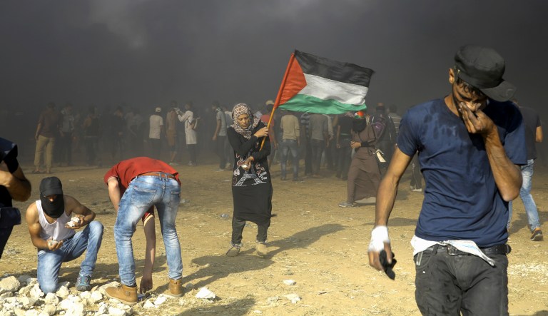 A Palestinian woman waves a national flag during a protest at the Gaza Strip's border with Israel, east of Khan Younis on May 15, 2018. Israel faced a growing backlash Tuesday and new charges of using excessive force, a day after Israeli troops firing from across a border fence killed dozens of Palestinians and wounded more than 2,700 at a mass protest in Gaza.