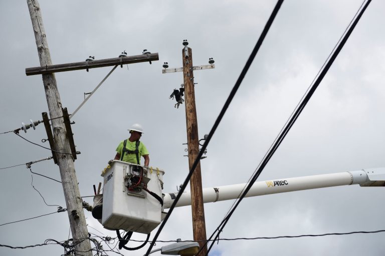 In this May 16, 2018 photo, a worker with Cobra Energy Company, contracted by the Army Corps of Engineers, installs power lines in the Barrio Martorel area of Yabucoa, a town where many people are still without power in Puerto Rico.  The devastation on Puerto Rico is just a blip compared to what the nation would feel in an attack on the electric grid, say experts.