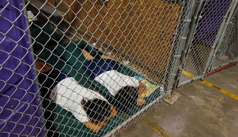 FILE - In this June 18, 2014 file photo, two female detainees sleep in a holding cell, as the children are separated by age group and gender, as hundreds of mostly Central American immigrant children are being processed and held at the U.S. Customs and Border Protection Nogales Placement Center in Nogales, Ariz.  President Donald Trump has seized on an error by liberal activists for tweeting photos of detainees at the U.S.-Mexico border in steel cages and blamed the current administration for separating immigrant children from their parents.  The photos were taken by The Associated Press in 2014, when President Barack Obama was in office.  