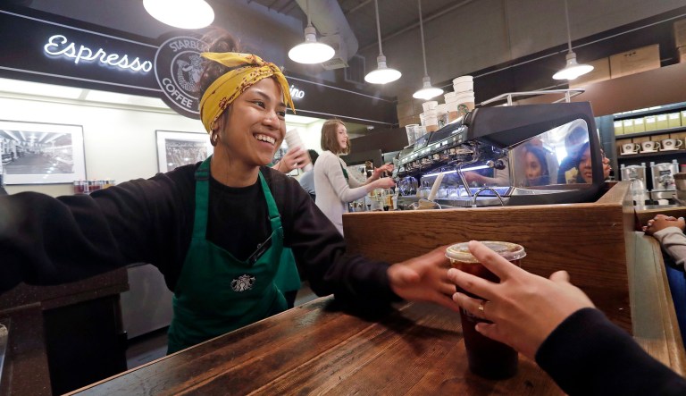 Barista Sarah Dacuno serves a customer at a Starbucks, commonly referred to as the original Starbucks, in the Pike Place Market Tuesday, May 29, 2018, in Seattle.