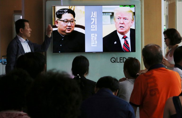 People watch a TV screen showing file footage of U.S. President Donald Trump, right, and North Korean leader Kim Jong Un during a news program at the Seoul Railway Station in Seoul, South Korea, Tuesday, June 5, 2018. The White House says Trump's meeting with Kim is set for 9 a.m. on June 12 in Singapore, which is 9 p.m. on June 11 on the U.S. East Coast. The signs read: " Negotiations of the century."
