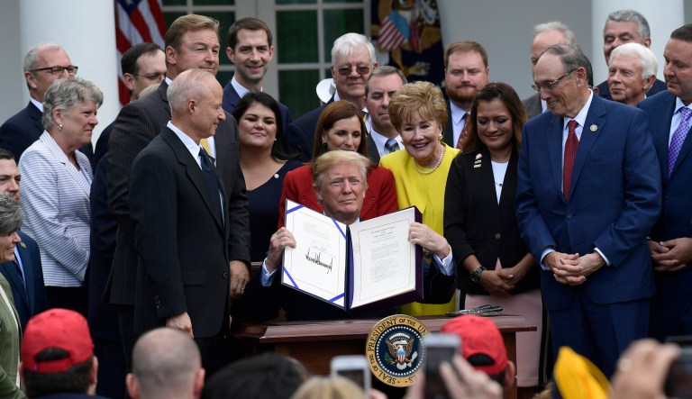 President Trump holds up the "VA Mission Act of 2018" that he just signed during a ceremony in the Rose Garden of the White House in Washington, D.C., on Wednesday. The bill will expand private care for veterans as an alternative to the troubled Veterans Affairs health system.