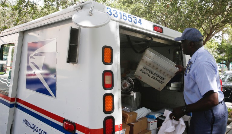 Elston Bradshaw, a mail carrier for the United States Postal Service closes a mail truck door after delivering mail to an apartment complex on Thursday, June 14, 2018, in Aventura, Fla.