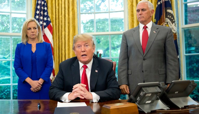 President Donald Trump, center, with Homeland Security Secretary Kirstjen Nielsen, left, and Vice President Mike Pence, right, addresses members of the media before signing an executive order to end family separations, during an event in the Oval Office of the White House in Washington, Wednesday, June 20, 2018. 
