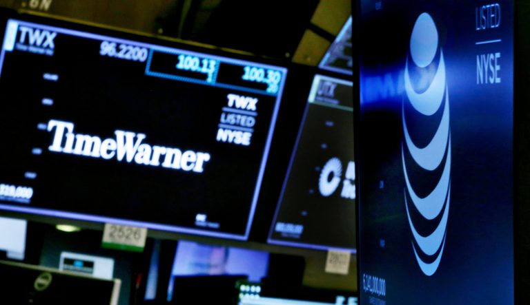 In this Wednesday, June 13, 2018 photo, the logos for Time Warner and AT&T appear above alternate trading posts on the floor of the New York Stock Exchange. 