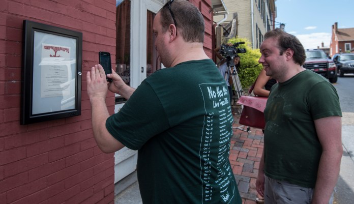 Brandon Hintze, left, of Alexandria, Va., and Brian Tayback, of Shrewsbury, Pa., take a photo of the menu outside of the Red Hen Restaurant, Saturday, June 23, 2018, in Lexington, Va. White House press secretary Sarah Huckabee Sanders said Saturday in a tweet that she was booted from the Virginia restaurant because she works for President Donald Trump. Sanders said she was told by the owner of The Red Hen that she had to "leave because I work for @POTUS and I politely left."