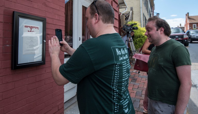 Brandon Hintze, left, of Alexandria, Va., and Brian Tayback, of Shrewsbury, Pa., take a photo of the menu outside of the Red Hen Restaurant, Saturday, June 23, 2018, in Lexington, Va. White House press secretary Sarah Huckabee Sanders said Saturday in a tweet that she was booted from the Virginia restaurant because she works for President Donald Trump. Sanders said she was told by the owner of The Red Hen that she had to "leave because I work for @POTUS and I politely left."