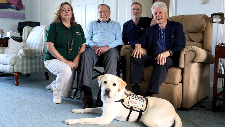 Former President George H.W. Bush, second left, poses for a photo with Sully, a yellow Labrador retriever who'll be his first service dog at his home in Kennebunkport, Maine.