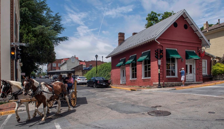 Tourists pass the Red Hen restaurant in Lexington, Va., Wednesday, June 27, 2018. The co-owner of the Virginia restaurant that refused to serve White House press secretary Sarah Sanders has resigned from a local business group.