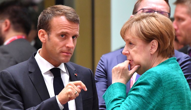 French President Emmanuel Macron speaks with German Chancellor Angela Merkel during a roundtable meeting at a European Union summit in Brussels on June 28, 2018.
