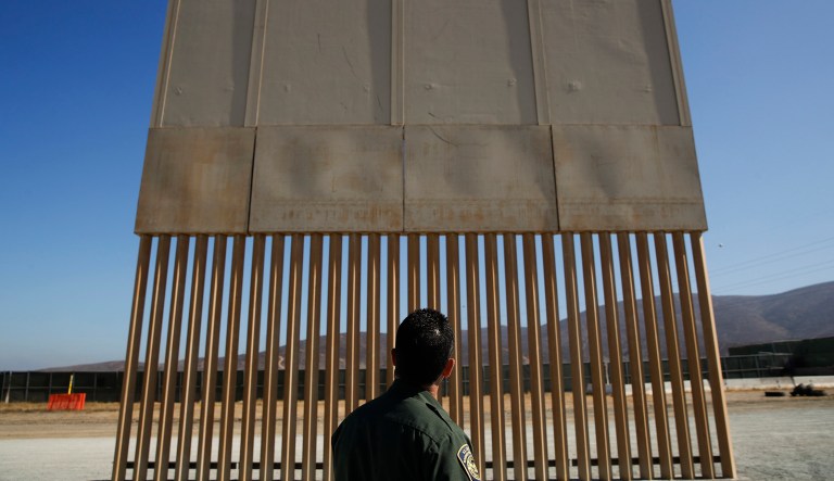 A U.S. Border Patrol agent looks at one of border wall prototypes Thursday, June 28, 2018, in San Diego.