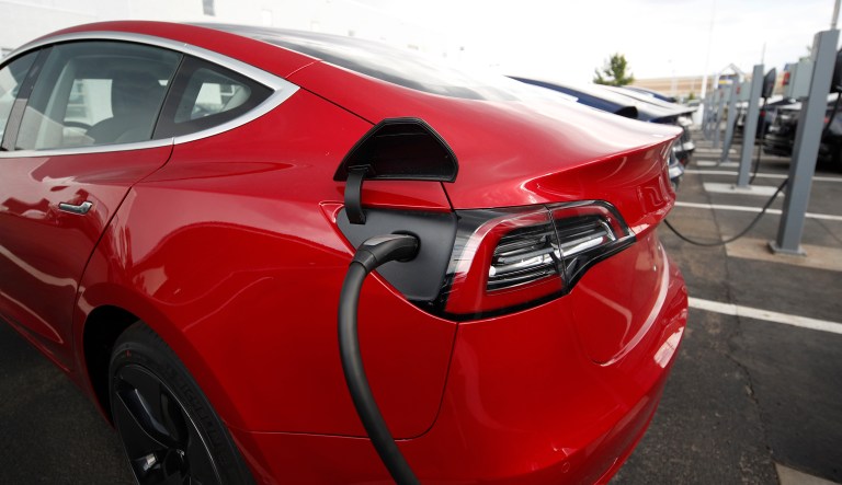 In this Sunday, July 8, 2018, photograph, 2018 Model 3 sedans charge while on display outside a Tesla showroom in Littleton, Colo.