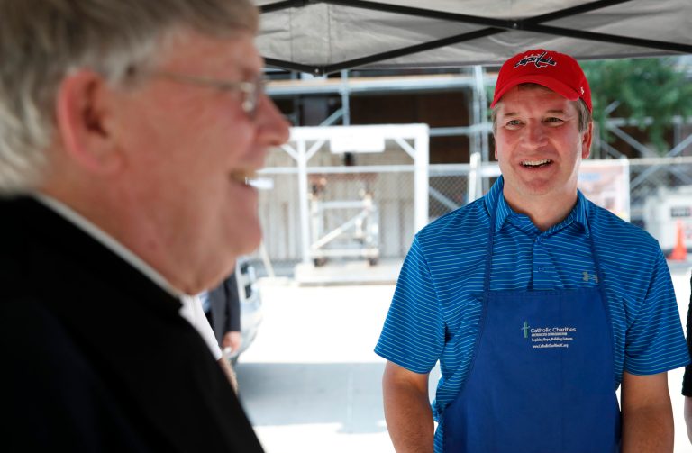 Monsignor John Enzler, left, President and CEO of Catholic Charities, Archdiocese of Washington, talks with Supreme Court nominee Brett Kavanaugh as he serves meals to the homeless as he volunteers with Catholic Charities, Wednesday, July 11, 2018 in Washington.