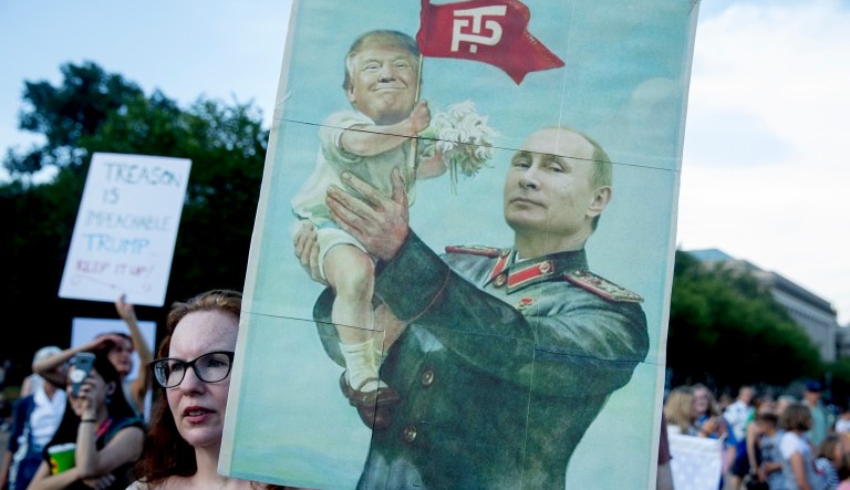 A woman holds a sign depicting Russian President Vladimir Putin and President Trump during a protest outside the White House on July 17, 2018, in Washington.