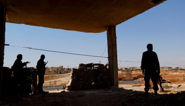 Syrian soldiers stand guard at their post overlooking the Damascus-Aleppo highway, in the central Syrian town of Rastan.