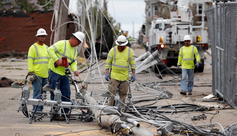 Utility workers repair downed power lines, Friday, July 20, 2018, in Marshalltown, Iowa. Several buildings were damaged Thursday evening by a tornado in the main business district in town including the historic courthouse.