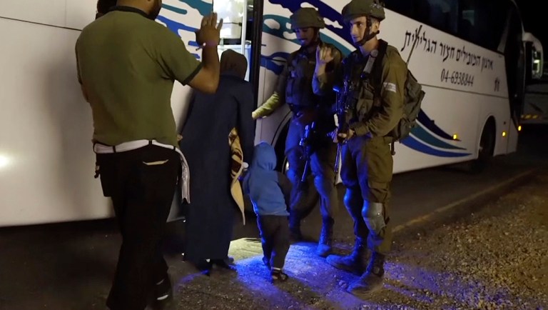 This image made from video released by the Israeli Defence Forces on Sunday shows a member of the White Helmets waving to Israeli soldiers as he and his family board a bus to Jordan. (Israeli Defence Forces via AP)