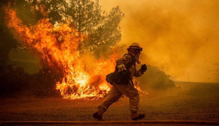 A firefighter runs while trying to save a home as a wildfire tears through Lakeport, Calif., on July 31, 2018.