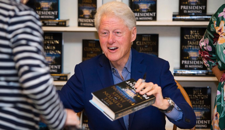 In a June 28, 2018, file photo, former President Bill Clinton holds a copy of "The President is Missing" at Book Revue, in Huntington, NY. The book, co-written with James Patterson, has more than 1 million sales in North America.