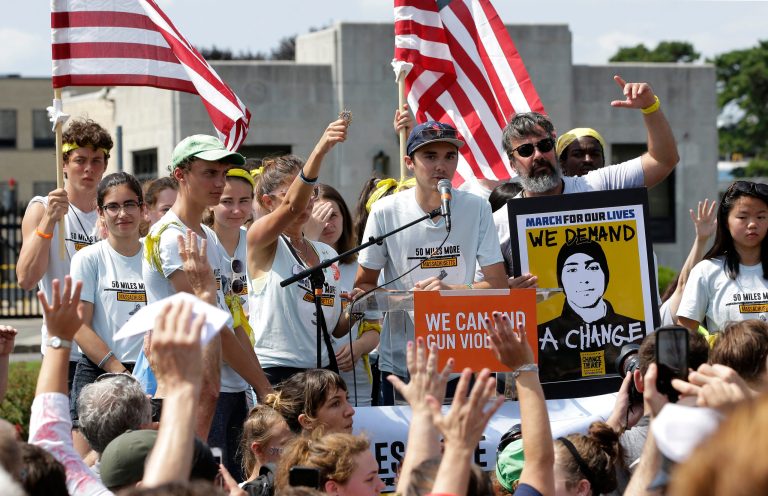 David Hogg, center, a survivor of the school shooting at Marjory Stoneman Douglas High School, in Parkland, Florida, addresses a rally in front of the headquarters of gun manufacturer Smith & Wesson, Sunday, Aug. 26, 2018, in Springfield, Mass.
