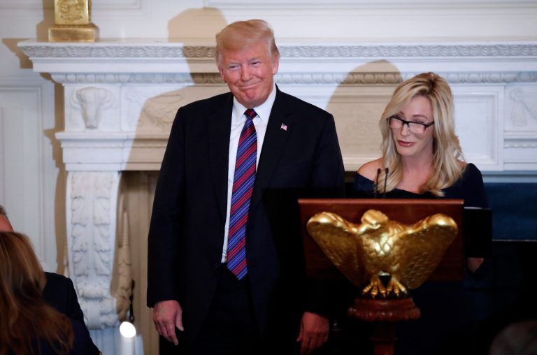 President Donald Trump smiles as pastor Paula White prepares to lead the room in prayer, during a dinner for evangelical leaders in the State Dining Room of the White House, Monday, Aug. 27, 2018.