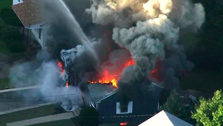 In this image take from video provided by WCVB in Boston, flames consume the roof of a home in Lawrence, Mass, a suburb of Boston.