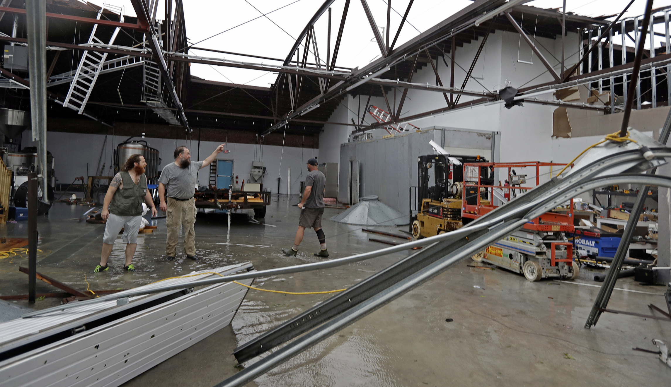 Ethan Hall, right, Michael Jenkins, center, and Nash Fralick, left, examine damage to Tidewater Brewing Co. in Wilmington, N.C., after Hurricane Florence made landfall Friday.