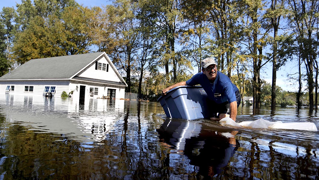 Kenny Babb gathers items that floated out of his garage, seen in the background, as the Little River continues to rise in the aftermath of Hurricane Florence in Linden, N.C.