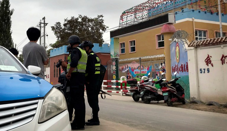 In this Aug. 30, 2018, photo, security personnel inspect camera equipment of journalists outside the Hotan City Kindness Kindergarten, where Meripet learnt her children are kept in Hotan, in western China's Xinjiang region. Meripet lives in exile in Turkey but her family is among tens of thousands swept up in the internment of more than one million Uighurs and other Muslim minorities and there is evidence the government is placing the children of detainees and exiles into dozens of orphanages across Xinjiang. 