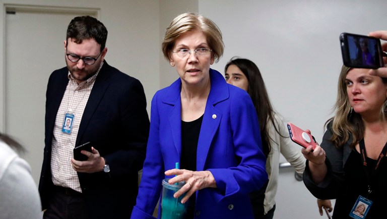 Sen. Elizabeth Warren, D-Mass., center, talks with reporters as she walks.