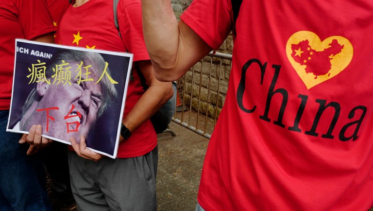 Pro-China protesters display a placard with Chinese words "Crazy man step down" during a protest against President Trump's trade war against China.