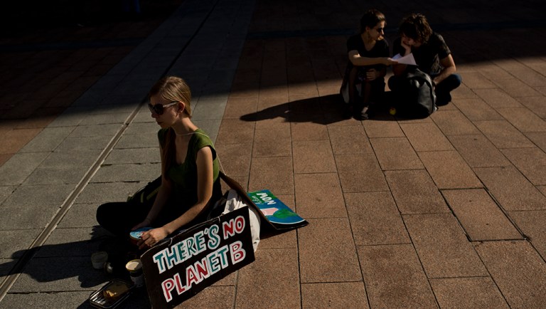 People listen to speeches during a protest demanding European Union leaders to honor their commitments to the 2015 Paris Agreement.