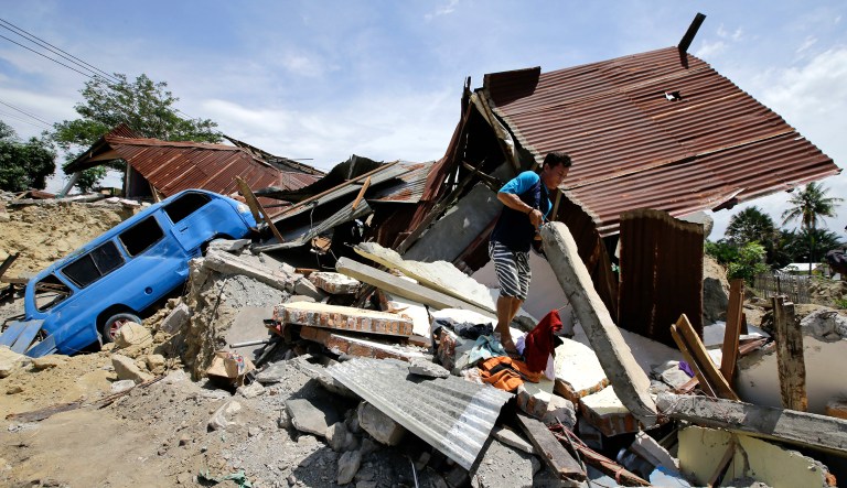 A man moves concrete from his toppled home at earthquake-hit Balaroa neighborhood in Palu, Central Sulawesi, Indonesia on Saturday. Search teams pulled bodies from obliterated neighborhoods in the disaster-stricken Indonesian city of Palu on Saturday as more aid rolled in and the government said it was considering making devastated areas into mass graves. 