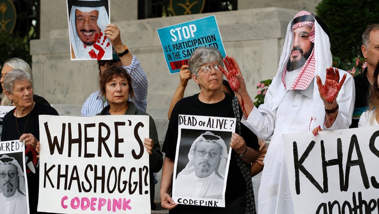 People hold signs at the Embassy of Saudi Arabia during protest about the disappearance of Saudi journalist Jamal Khashoggi.