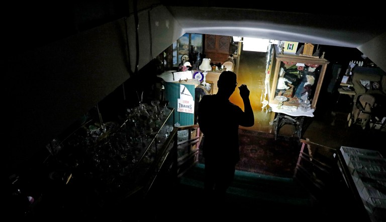 Chris Allen looks into the flooded lower level of an antique shop during a power outage in the aftermath of Hurricane Michael in Panama City, Fla.