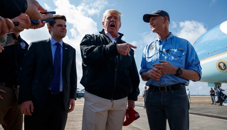 Gov. Rick Scott, R-Fla., right, looks on as President Donald Trump talks with reporters after arriving at Eglin Air Force Base to visit areas affected by Hurricane Michael, Monday, Oct. 15, 2018, in Eglin Air Force Base, Fla.