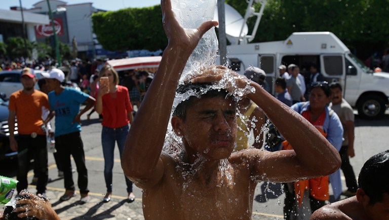Central American migrants making their way to the U.S. in a large caravan bathe using water from a fire hydrant at the main plaza in Tapachula, Mexico.