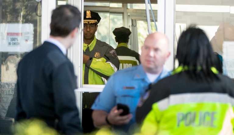 Metropolitan Police Second District Commander Melvin Gresham, accompanied by other police officers, stands at the broken front door of the offices of the local Fox broadcast affiliate after a man was shot by a security guard while trying to break into the lobby of the building, Monday, Oct. 22, 2018, in Washington.
