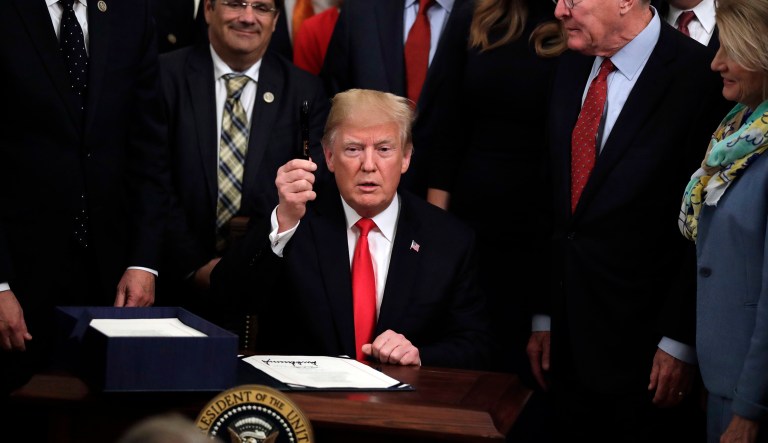 President Donald Trump holds a pen up after signing bipartisan legislation to confront the opioid crisis in the East Room of the White House, Wednesday, Oct. 24, 2018, in Washington.