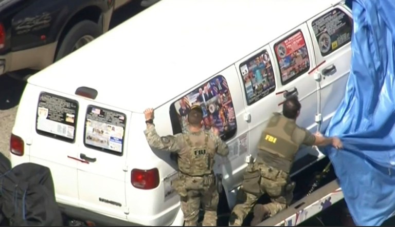This frame grab from video provided by WPLG-TV shows FBI agents covering a van after the tarp fell off as it was transported from Plantation, Fla., on Friday that federal agents and police officers have been examining in connection with package bombs that were sent to high-profile critics of President Donald Trump. The van has several stickers on the windows, including American flags, decals with logos and text.