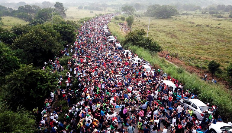 Members of a U.S.-bound migrant caravan stand on a road after federal police briefly blocked their way outside the town of Arriaga on Saturday.