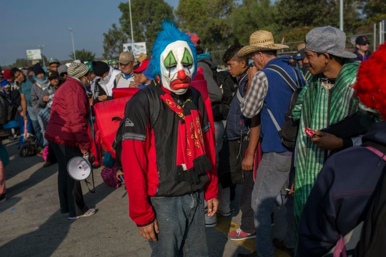 A Central American migrant, part of the caravan hoping to reach the U.S. border, stands among the crowd wearing a mask, while waiting to get a ride on a truck, in Celaya, Mexico.