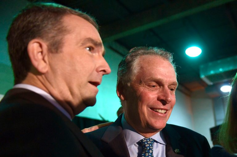 Virginia Gov. Ralph Northam, left, talks with former Virginia Gov. Terry McAuliffe, right, before the start of a news conference in the Crystal City neighborhood in Arlington, Va., Tuesday, Nov. 13, 2018. Amazon, which has grown too big for its Seattle hometown, said it will split its much-anticipated second headquarters between New York and northern Virginia.