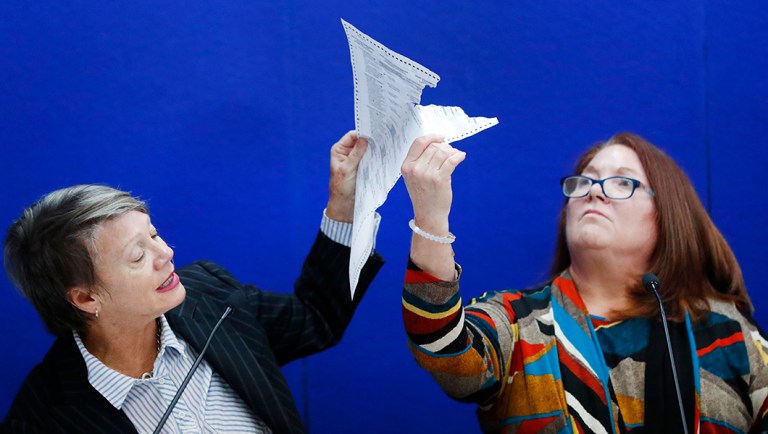 Canvassing Board chair Judge Betsy Benson, left, and board member Judge Deborah Carpenter-Toye, right, show political lawyers one of the ballots that was damaged during the recount in Broward County.