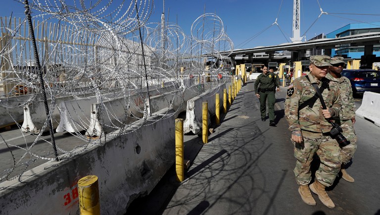 U.S. Border Patrol agents and members of the military pass concertina wire during a tour of the San Ysidro port of entry Friday, Nov. 16, 2018, in San Diego. As thousands of migrants in a caravan of Central American asylum-seekers converge on the doorstep of the United States, what they won't find are armed American soldiers standing guard. Instead they will see cranes installing towering panels of metal bars and troops wrapping concertina wire around barriers while military helicopters fly overhead. (AP Photo/Gregory Bull)