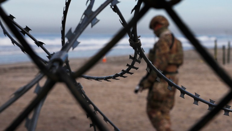 A U.S. Border Patrol agent stands on the U.S. side of the border.