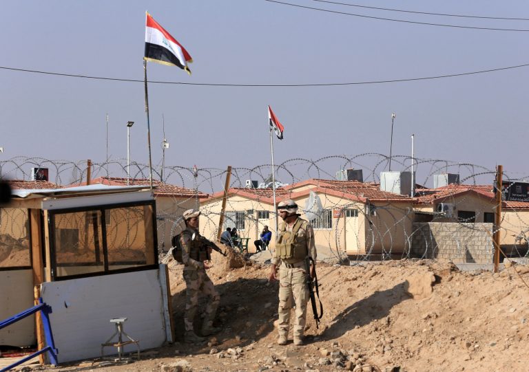 In this Tuesday, Nov. 13, 2018 photo, Iraqi soldiers stand guard with their weapons on the border crossing with Syria, in Qaim, Anbar province, Iraq. More than a year after this Iraqi town was freed from the Islamic State group, booms from airstrikes still echo and columns of smoke are visible, rising beyond the earthen berms and concrete walls marking the border with Syria. On the other side, the fight is raging to capture one of the militant groupâs last enclaves.