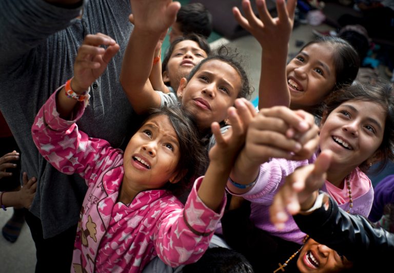 Migrants children, who are part of the Central American caravan, vie for candy tossed out to them by a social worker at a shelter in Tijuana, Tuesday, Nov. 20, 2018.