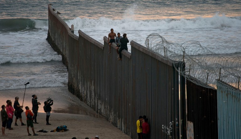 Two Honduran immigrants pose for portraits astride the border structure that separates Mexico from the U.S. seen from Tijuana, Mexico, Wednesday, Nov. 21, 2018. The two migrants where posing for a documentary maker. 